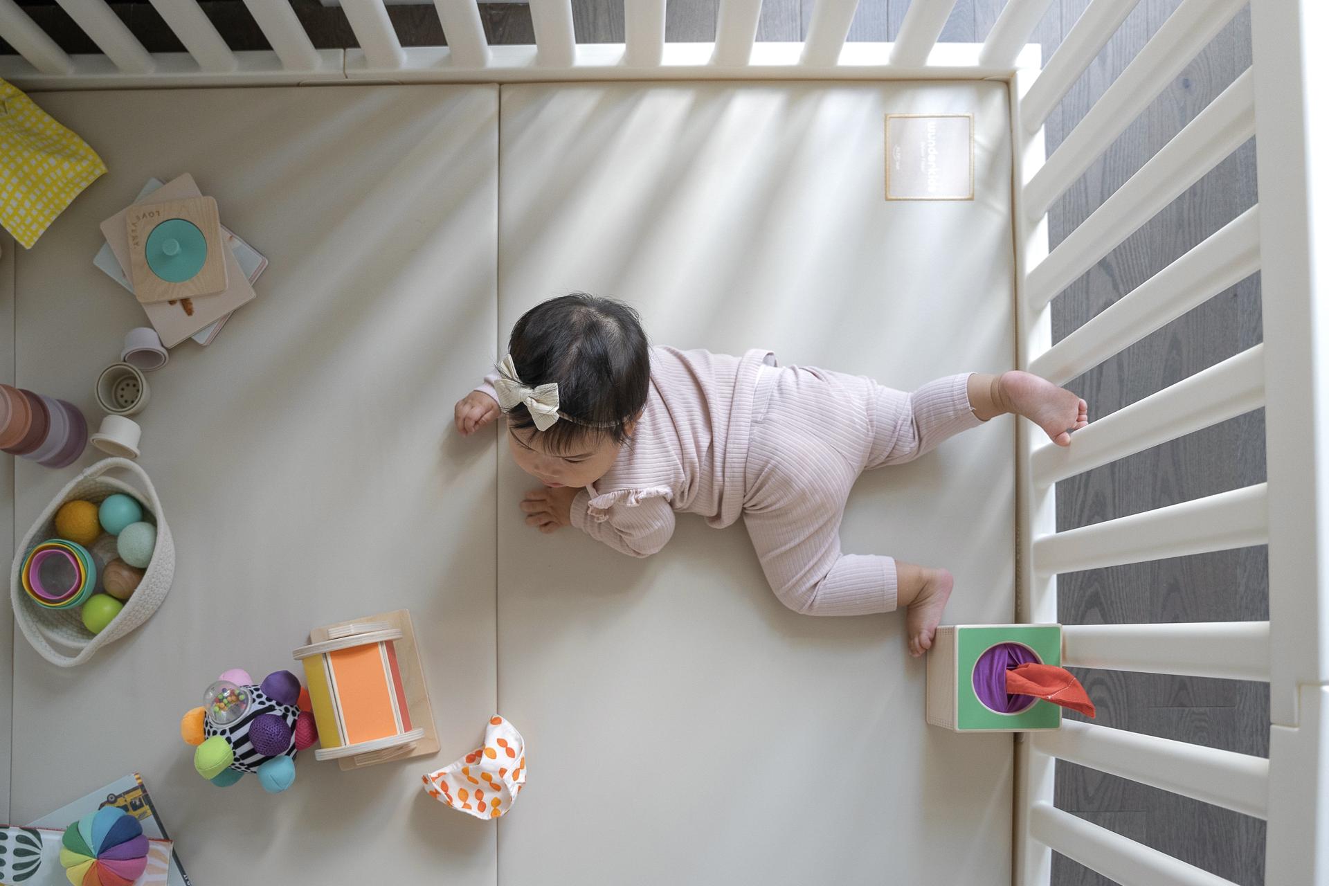 Infant enjoying tummy time on Wunderkids playmat surrounded by colourful