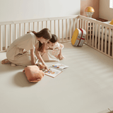 Mom and baby girl reading a book inside the Woodley Babyroom with Playmat