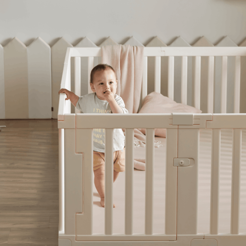 baby securely gripping the Woodely Babyroom Fence with his little hands