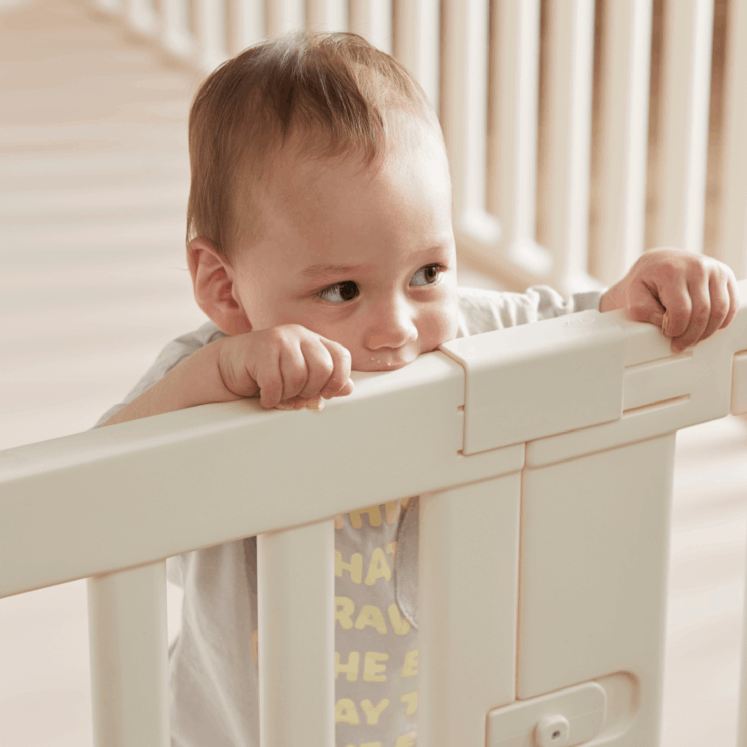 A cute baby enjoying their time by playfully biting onto the Woodely Babyroom Fence