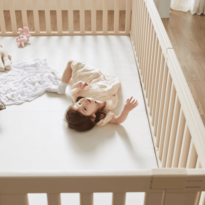 Baby girl lying down on Wunderkids Playmat inside Woodley Babyroom